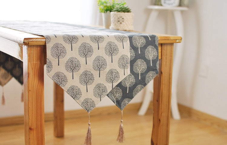 A table runner with a tree pattern draped over a wooden dining table in a bright, modern room.